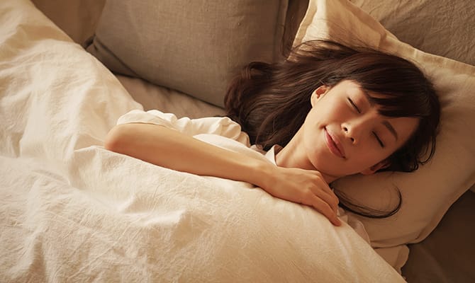 ベッドで眠る女性イメージ画像